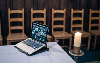 Laptop op tafel met kaars in kring - foto Nederlands Dagblad